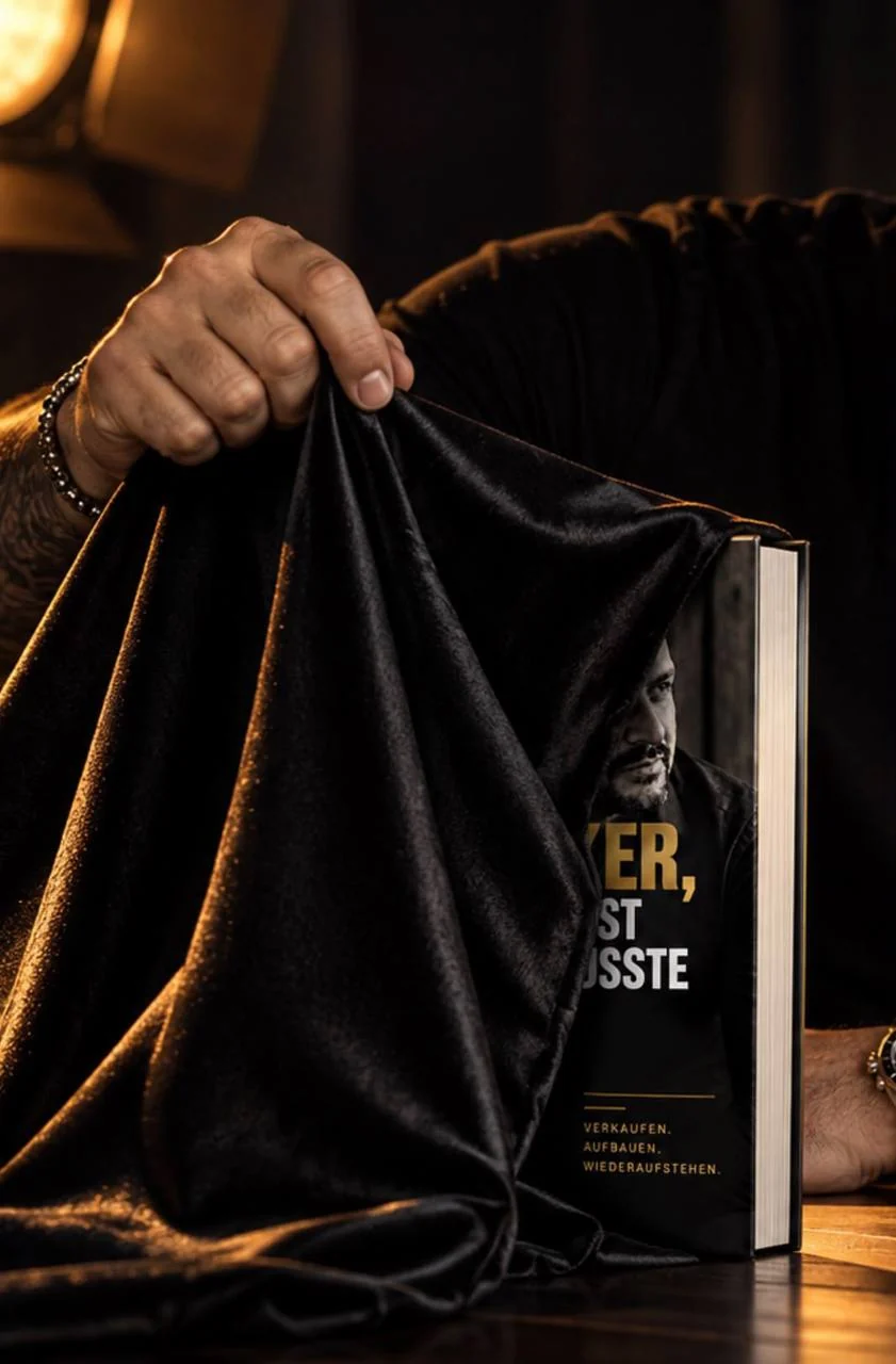 Eine Hand zieht ein schwarzes Samttuch von dem Buch „Der Dealmaker, der sich selbst verkaufen musste“ von Ivan Gentile